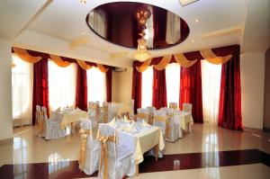 un salón de banquetes con mesas y sillas blancas y ventanas en Chervona Gora, en Mukácheve