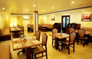 a restaurant with tables and chairs in a room at Hotel Horizon International in Guruvāyūr