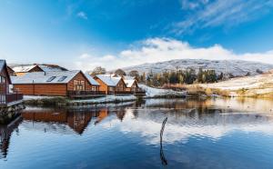 una fila de casas junto a un río con nieve en Lodge 9 Glengoulandie Lodges, en Aberfeldy