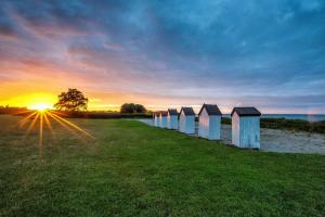 Dalby鲱鱼露营地的日落时在海滩上排排的海滩小屋