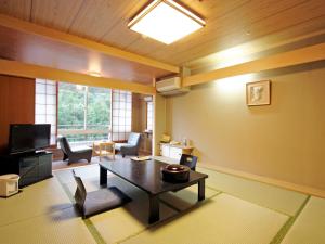 a living room with a table and a tv at Yumoto Kanko Hotel Saikyo in Nagato