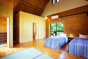two beds in a room with wooden walls at Lodge Kiyokawa in Bungoono
