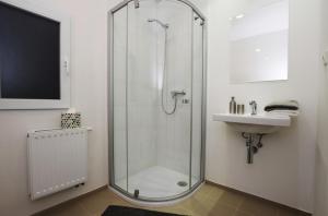 a bathroom with a glass shower and a sink at Císařka Apartment in Prague