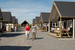 a man and a woman walking down a street with houses at Thyborøn Cottages in Thyborøn