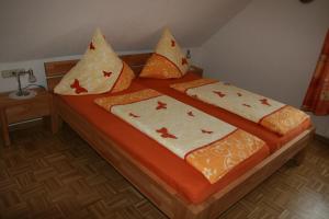 a bed with orange and white sheets and pillows at Weingut & Gästehaus Stephan Kohl in Neumagen-Dhron