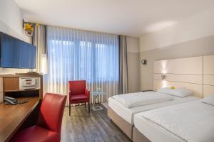 a hotel room with a bed and a desk and a chair at Ferrotel Duisburg - Partner of SORAT Hotels in Duisburg +26 photos