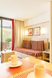 ein Wohnzimmer mit einem Sofa und zwei Tassen auf einem Tisch in der Unterkunft Pierre & Vacances Le Moulin des Cordeliers in Loches