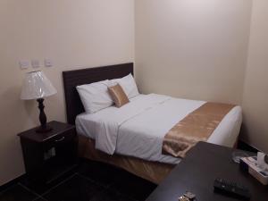 ein Schlafzimmer mit einem Bett und einem Tisch mit einer Lampe in der Unterkunft Lake Hotel in Mūkhī