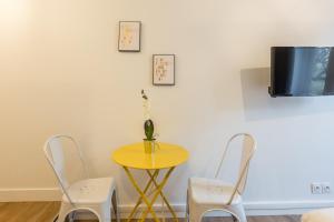 a yellow table with two chairs and a tv on a wall at Apartments WS St Germain - Quartier Latin in Paris