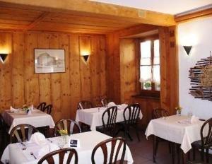d'une salle à manger avec des tables blanches et des murs en bois. dans l'établissement Chez Gilles hôtel resto bar SA, à La Chaux-de-Fonds