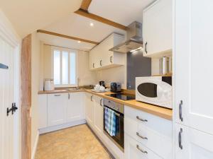 cocina con armarios blancos y microondas en St Kenelm, en Winchcombe