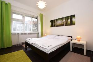 a bedroom with a bed and a window with green curtains at Císařka Apartments in Prague