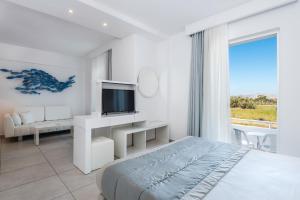 a white bedroom with a bed and a television at Gaia in Style - Adults Only in Tigaki