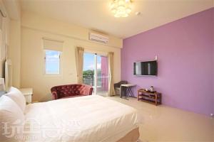a bedroom with a white bed and a purple wall at Hai Bed and Breakfasts in Taitung City