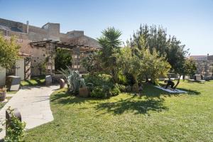 un giardino con cactus e alberi e un edificio di Hotel Maison Tresnuraghes a Tresnuraghes