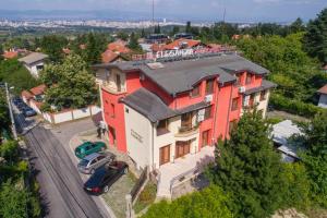 a red house with a car parked in front of it at Eleganza Family Hotel in Sofia