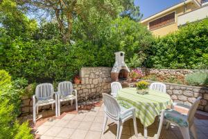a patio with a table and chairs and a stone wall at Apartments Emma in Mali Lošinj