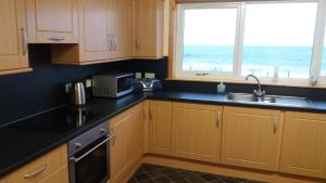 a kitchen with wooden cabinets and a sink and a window at Mey Cliff Cottage in Scarfskerry