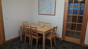 un tavolo in legno con 4 sedie in una stanza di Mey Cliff Cottage a Scarfskerry Altre 12 foto