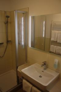 ein Bad mit einem Waschbecken, einer Dusche und einem Spiegel in der Unterkunft Hotel Haus am Meer in Graal-Müritz