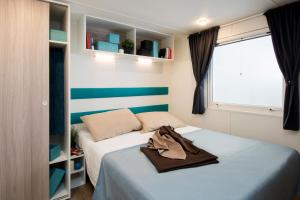 niewielka sypialnia z 2 łóżkami i oknem w obiekcie Toscana Bella Camping Village w mieście Vada