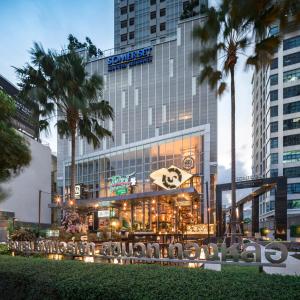 a building with a restaurant and palm trees in front of it at Somerset Sukhumvit Thonglor in Bangkok