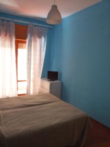 ミラッツォにあるMare Limpidoの青い壁のベッドルーム1室、窓付きのベッド1台が備わります。