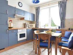 a kitchen with blue cabinets and a table and chairs at Comfortable Apartment in Kuhlungsborn Near Sea in Kühlungsborn