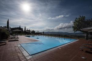 a large swimming pool with the sun in the sky at Il Convento di Monte Pozzali in Massa Marittima