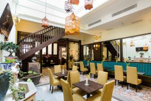 a restaurant with tables and chairs and a staircase at Aava Malacca Hotel in Melaka