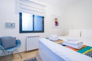 a bedroom with a bed and a chair and a window at Colony Suites - Hildesheimer St. in Jerusalem