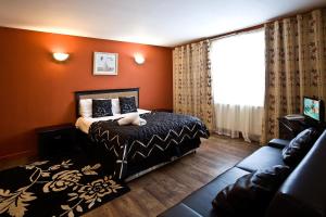 a bedroom with orange walls and a bed and a couch at Desalis Hotel London Stansted in Elsenham