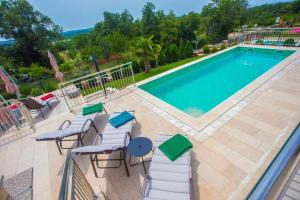 una imagen de una piscina con sillas y mesa en Villa Sunce, en Kaštelir