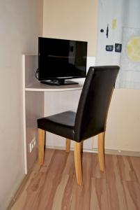 una silla negra sentada frente a un escritorio con TV en Kambarių nuoma - Šiauliai SAURIDA, en Šiauliai