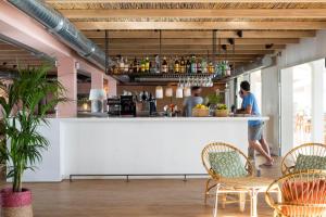a bar with chairs and a man standing at a counter at Hostal la Savina in La Savina