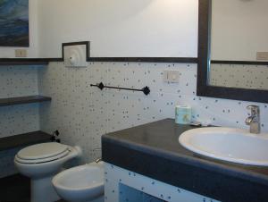 a bathroom with a sink and a toilet and a mirror at Residence L'uliveto in Gioiosa Marea