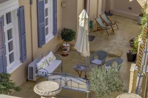 un patio con sillas, mesas y una sombrilla en Arhontiko Ermoupolis, en Ermoupoli