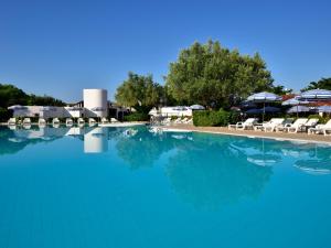 a large swimming pool with chairs and umbrellas at TH Simeri - Simeri Village in Simeri Mare