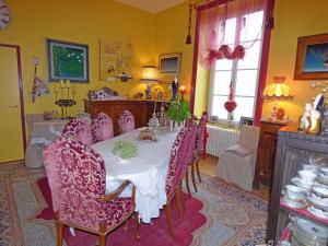 La Demeure aux Hortensias في Pleurtuit: غرفة طعام مع طاولة مع كراسي أرجوانية