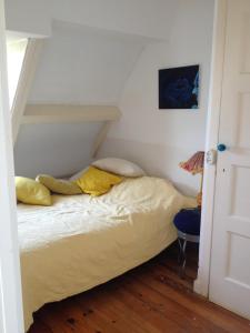 een bed met gele kussens in een kamer bij Het Witte Huis in Amsterdam