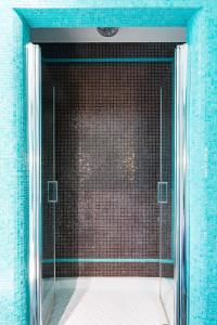 ローマにあるRooms Roma - Montiの青いタイルのバスルーム(ガラス張りのシャワー付)
