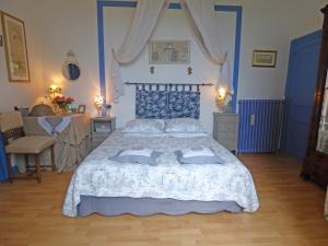 a bedroom with a blue and white bed and a table at La Demeure aux Hortensias in Pleurtuit