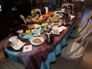 una mesa larga con comida y bebidas. en Chambres d'Hôtes La Villa des Hortensias, en Berck-sur-Mer