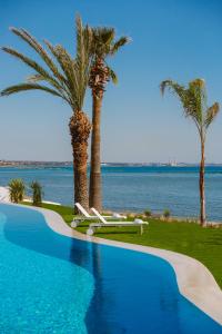 a swimming pool with two palm trees and the ocean at Lebay Beach Hotel in Larnaka