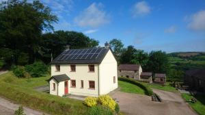 Treberfedd Farm Cottages and Cabins في لامبيتر: منزل أبيض مع لوحات شمسية على السطح