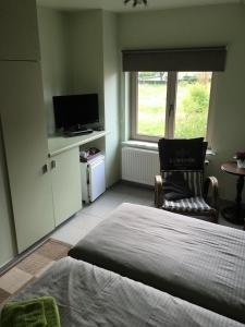 a bedroom with a bed and a chair and a window at Logies Ternier - Het Victorhuis in Nieuwpoort