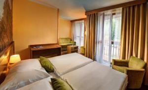 Cette chambre comprend 2 lits et une fenêtre. dans l'établissement Hotel FIS, à Štrbské Pleso