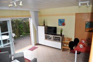 a living room with a tv and a table with chairs at Ferienhaus Exner hinter dem Deich in Cuxhaven