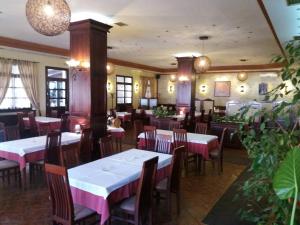 Un restaurante con mesas y sillas blancas y plantas. en Guesthouse "Kod Čileta", en Kovin