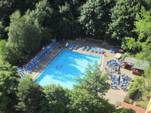 una vista aérea de una gran piscina con sillas azules en Ferienwohnung-Apartment-Seeblick-in-Plaza-Marit-Residenz, en Timmendorfer Strand